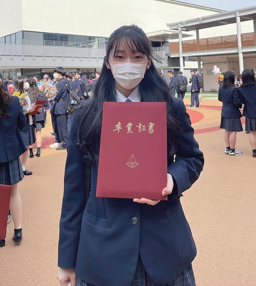 Anna Nishida poses with her diploma during her high school graduation ceremony