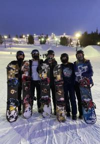 group of students pose at Lake Tahoe in snow gear holding their snowboards