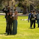 A diverse group of students show peace signs as they walk across the UC Davis Quad 