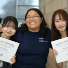 UC Davis student assistant Nicole Purba poses with two international students as they hold up their certificates