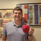 headshot of UC Davis International programs instructor Thomas Hardy posing with "World's bet teacher" mug