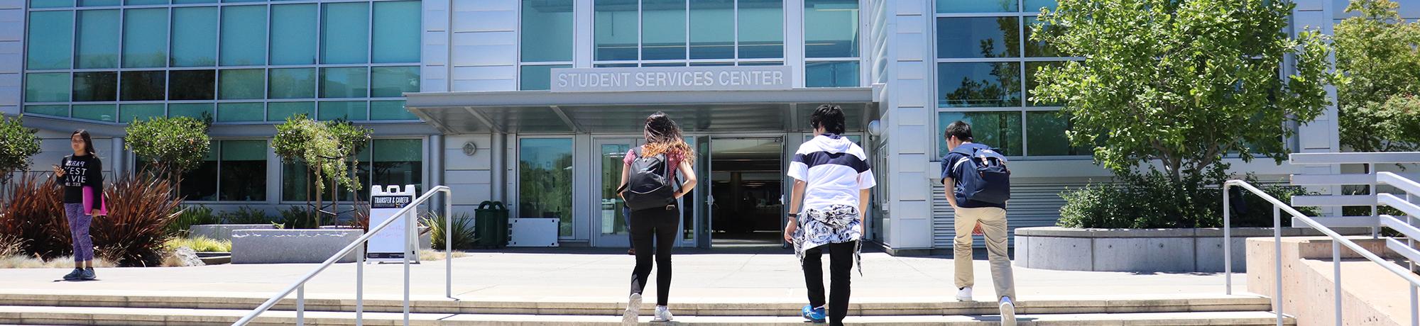 students walking up to student services building