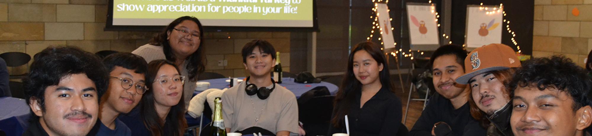a group of international students pose at a table during their Thanksgiving celebration