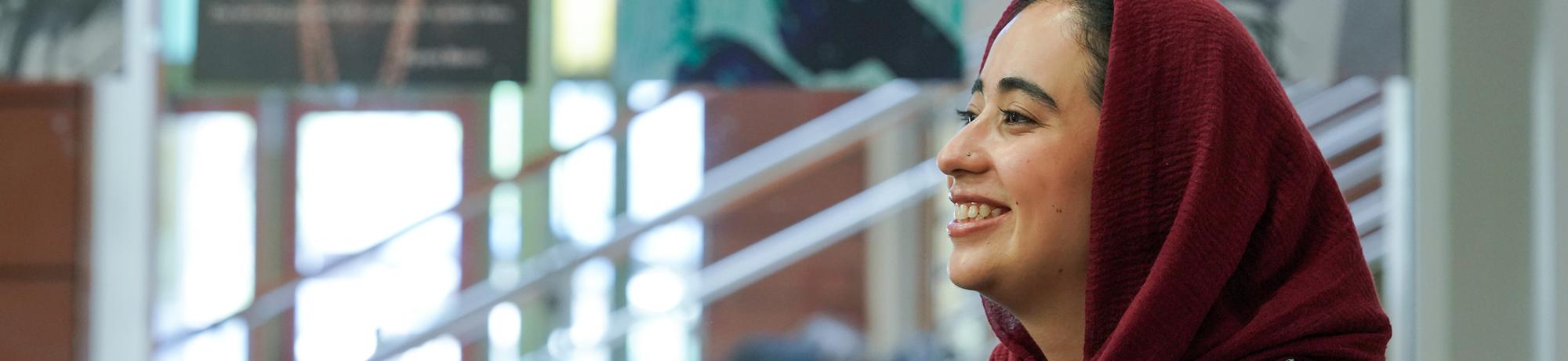 UC Davis student in headscarf smiles while sitting on campus